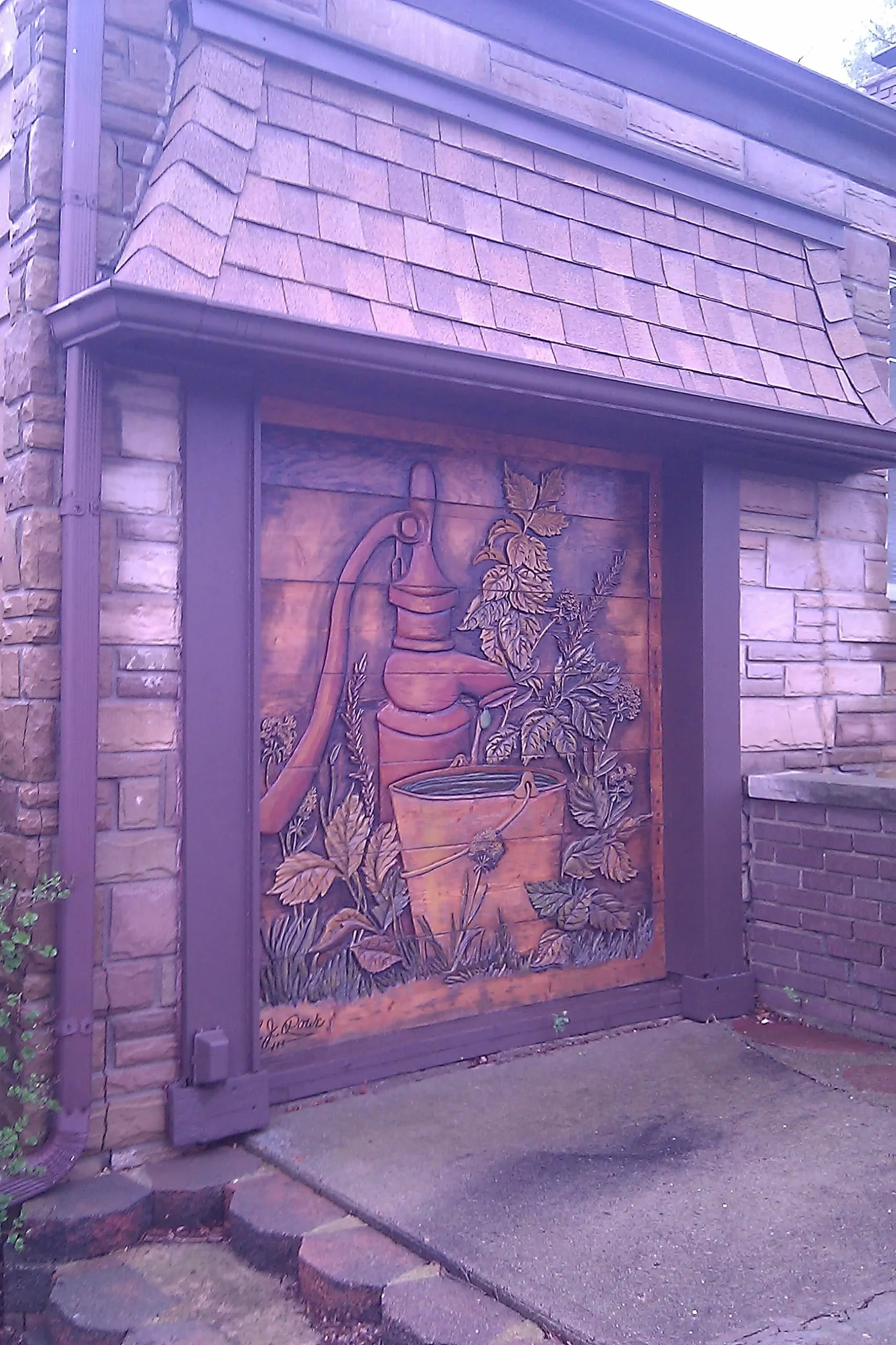a wooden garage door with a water pump and bucket carving