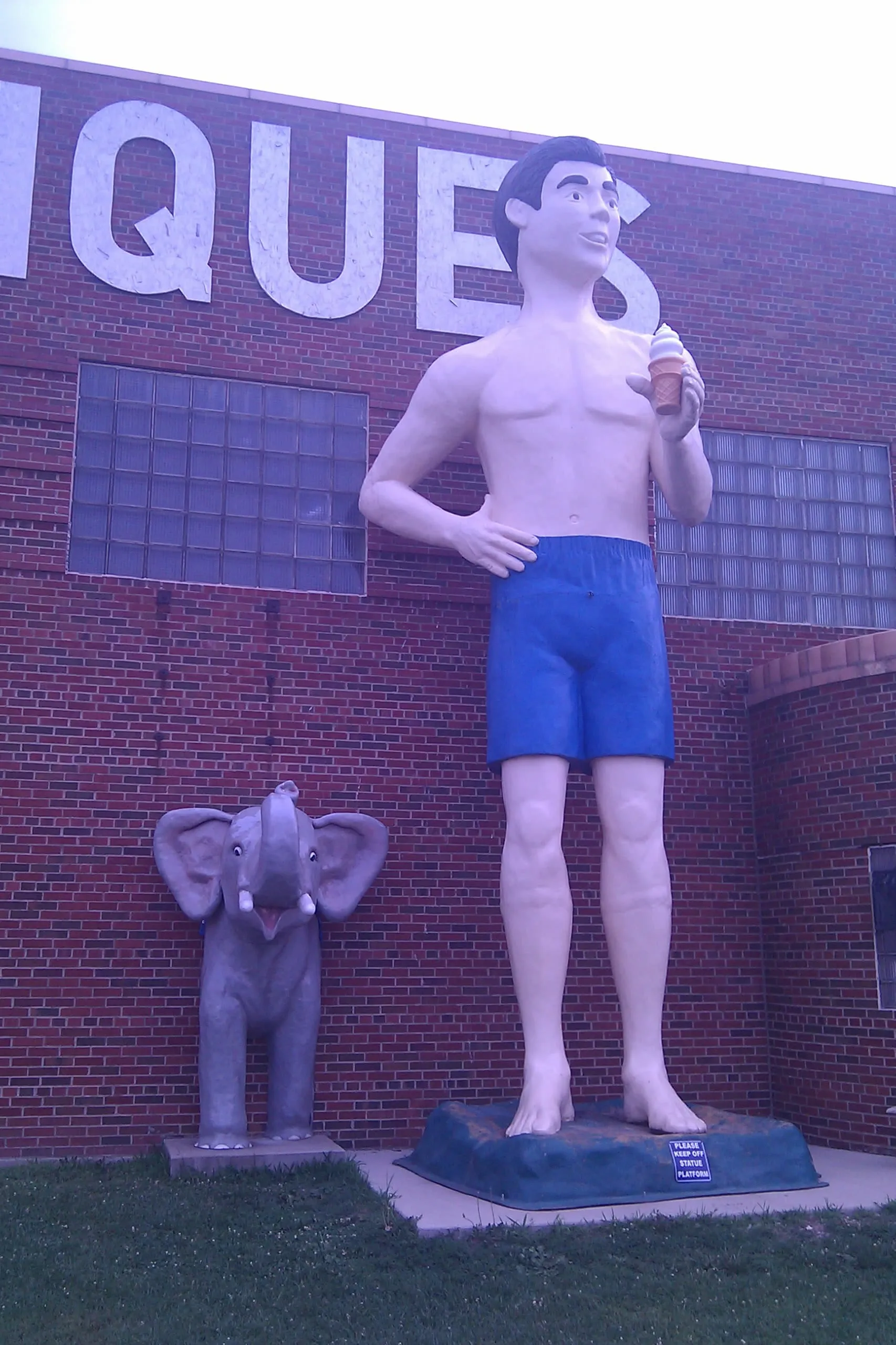 a muffler man and a fiberglass elephant outside an antiques shop