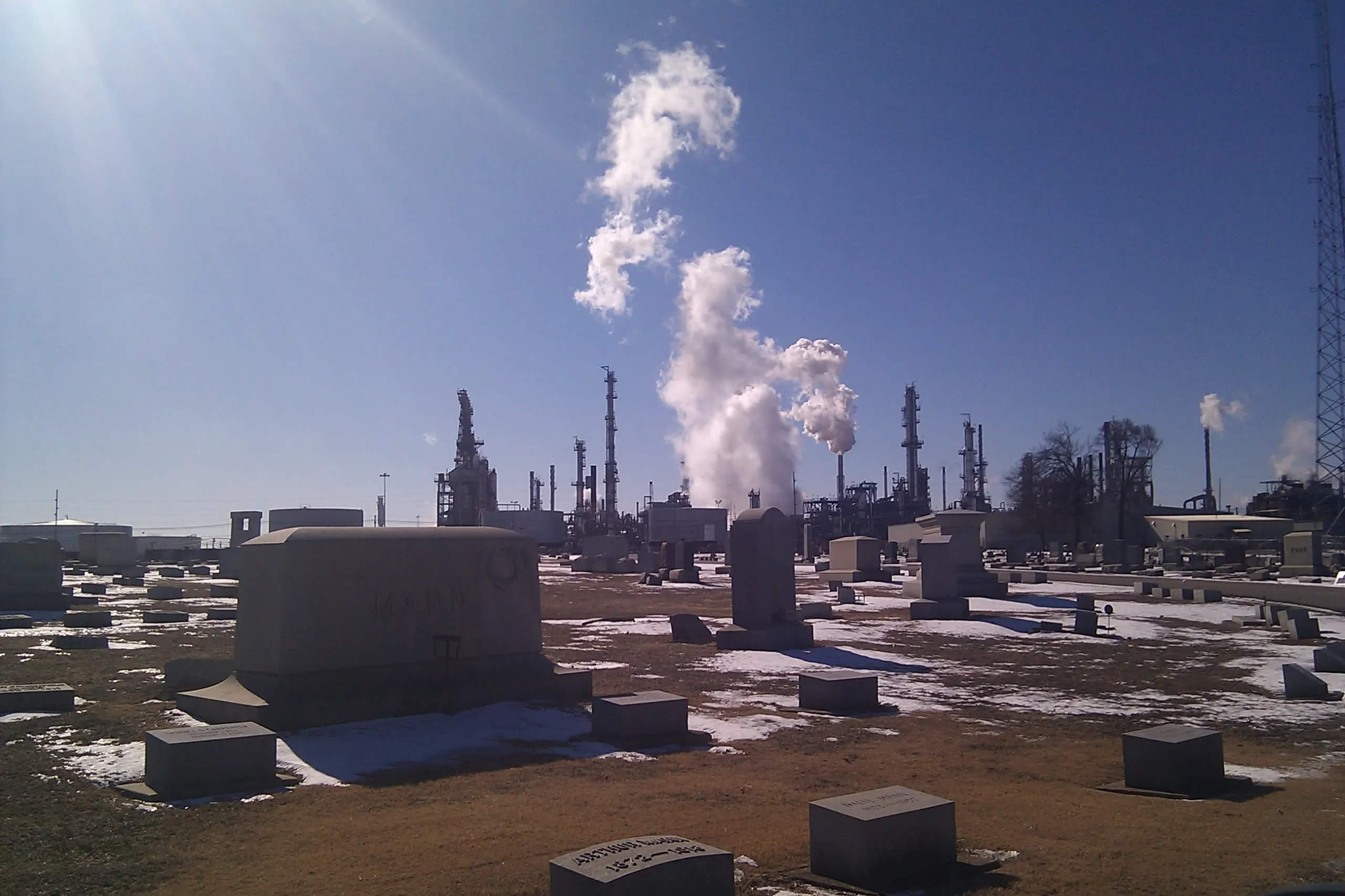 a cemetery behind a large factory plant