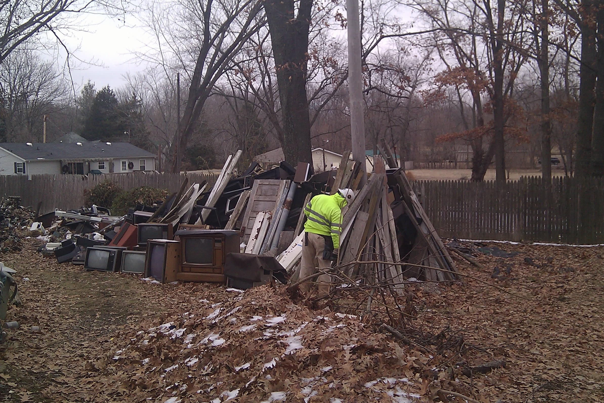 sorted junk piles in a backyard around the electric pole