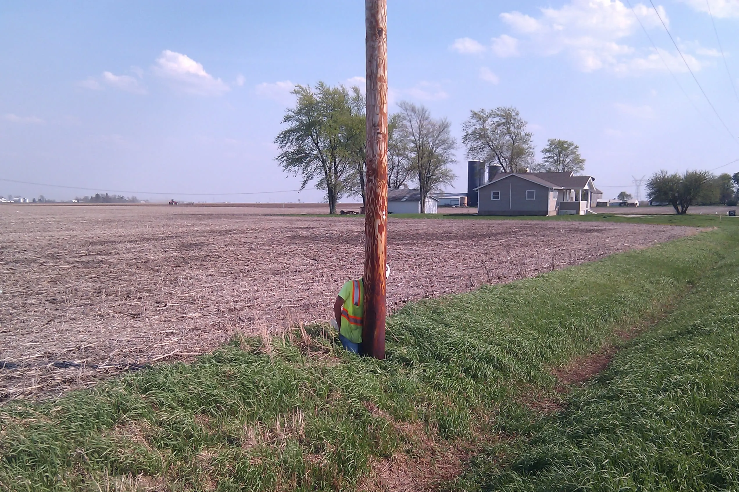 worker in a non-backfilled hole for a replacement electric pole